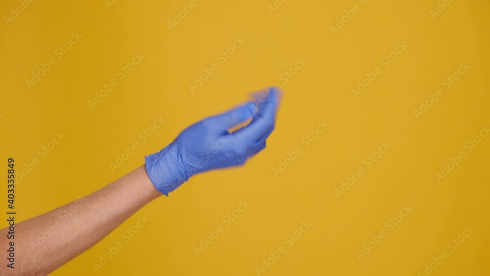 Close up of male hand in medical protective gloves making gesture Come closer, isolated on yellow studio background with copy space for advertisement. Body language concept. Pandemic Covid 19 concept Close up of male hand in medical protective gloves making gesture Come closer, isolated on yellow studio background with copy space for advertisement. Body language concept. Pandemic Covid 19 concept
