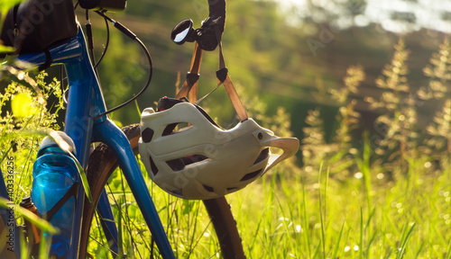 Bicycle with a helmet hanging on the handlebars on green grass background.