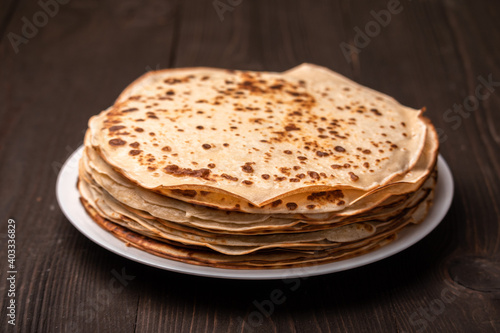 stack of pancakes on a plate on a dark wooden table
