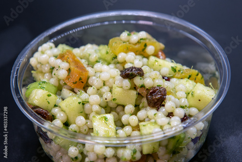 Lemon Herb Couscous served by the pound in clear plastic container for presentation of the savory contents