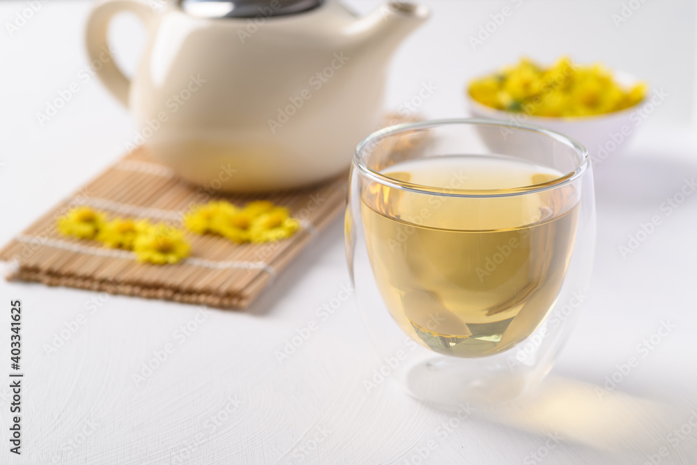 Organic Chrysanthemum flower tea in a cup and teapot on white background, Healthy Herbal drink Organic Chrysanthemum flower tea in a cup and teapot on white background, Healthy Herbal drink