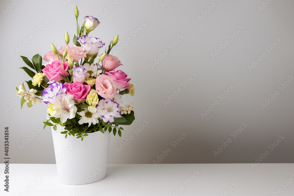 mock up bouquet of roses, daisies, lisianthus, chrysanthemums, unopened buds in a white paper box on a white table and wall.