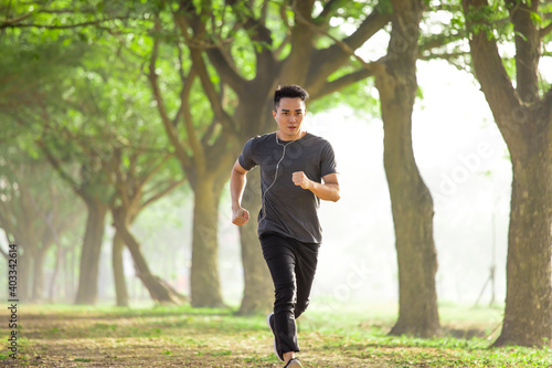 Asian young Man running in the forest on foggy at morning