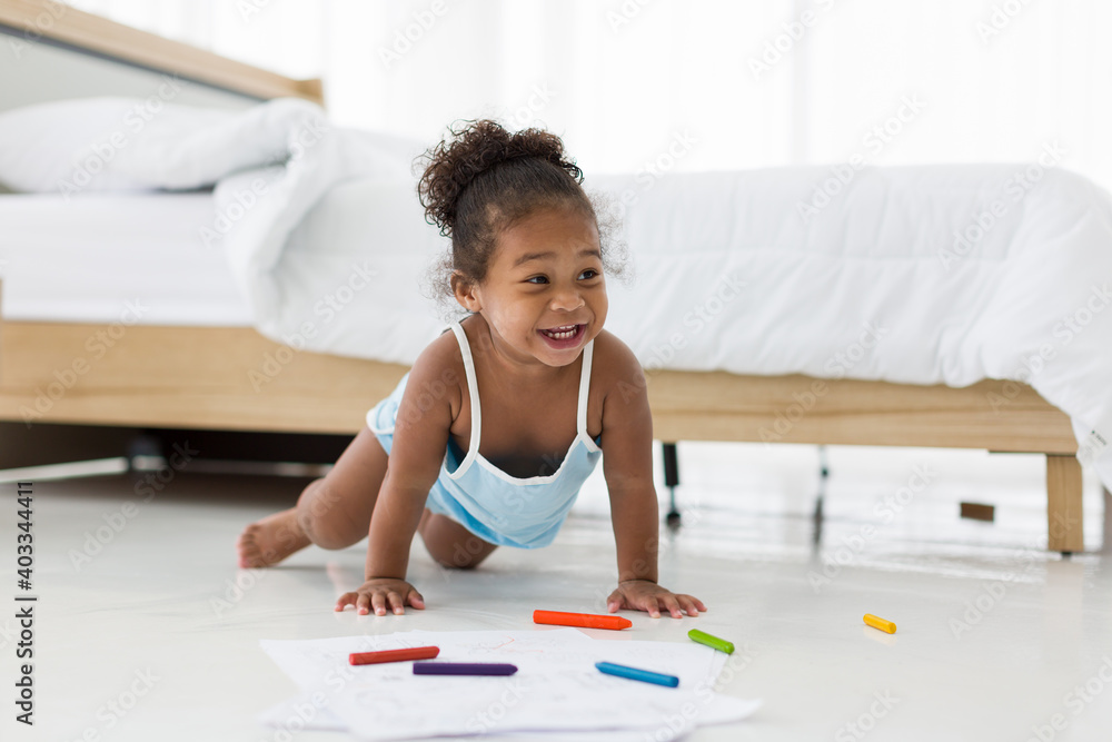 African American toddler little girl playing and drawing on floor in living room at home African American toddler little girl playing and drawing on floor in living room at home