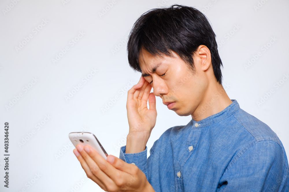 目の疲れや頭痛に悩む男性 スマートフォン 現代病 目の疲れや頭痛に悩む男性 スマートフォン 現代病