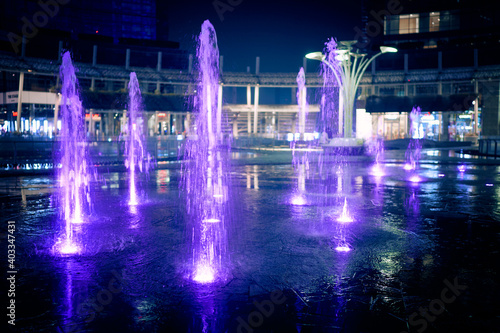Milan, Italy - December 17, 2020. Illuminated splashing water fountains in Gae Aulenti square surrounded by modern skyscrapers. Porta Garibaldi district. Financial district night view.