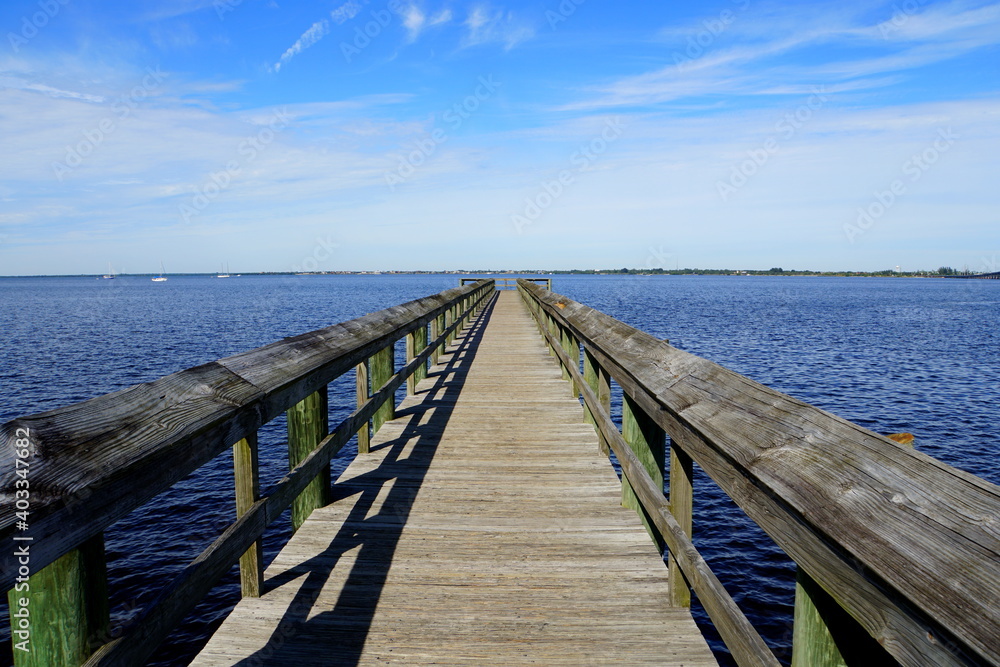 Naklejka premium The view of a wooden pier by the blue ocean Punta Gorda, Florida, U.S