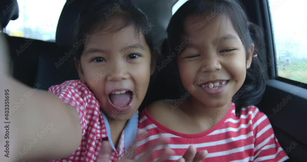 Two asian girls waving hands to say hi in video call in the car Two asian girls waving hands to say hi in video call in the car