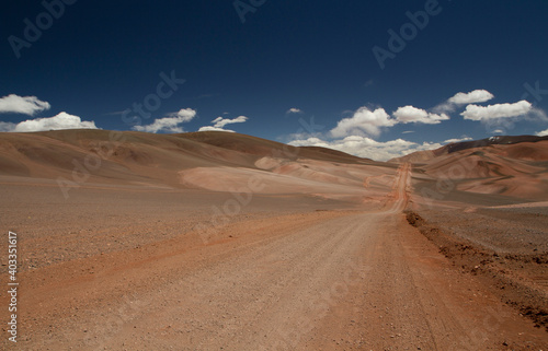 The dirt road high in the Andes mountains. Traveling along the route across the arid desert dunes and mountain range. The sand and death valley under a deep blue sky in La Rioja  Argentina.