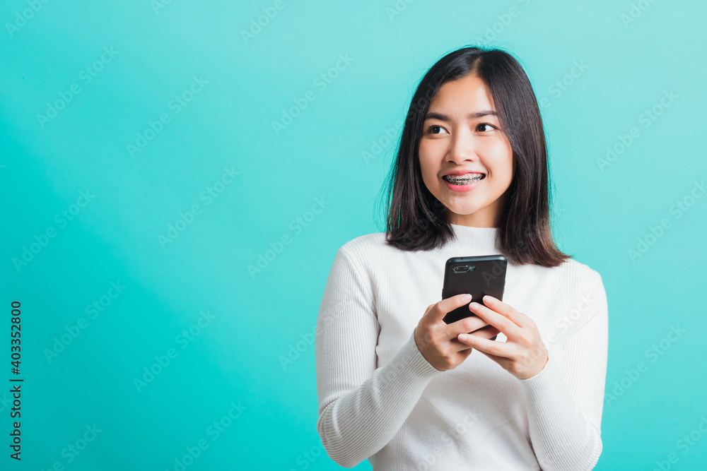 Portrait of Asian woman smile she holding and typing text message on a smartphone, female excited cheerful her reading mobile phone some social media isolated on a blue background, Technology concept Portrait of Asian woman smile she holding and typing text message on a smartphone, female excited cheerful her reading mobile phone some social media isolated on a blue background, Technology concept