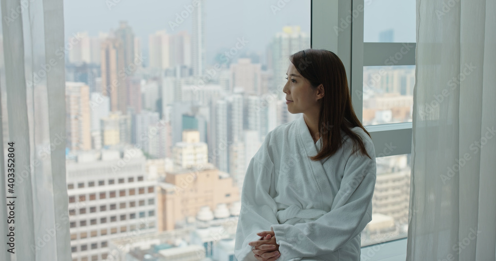 Woman with bathrobe and open the curtain to enjoy the view from window at morning