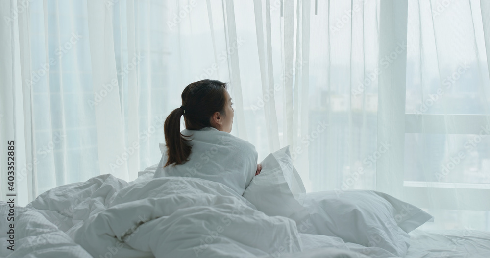 Woman lay down on bed and look outside the window Woman lay down on bed and look outside the window