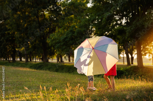 Two child playing  under umbrella at sunset time
