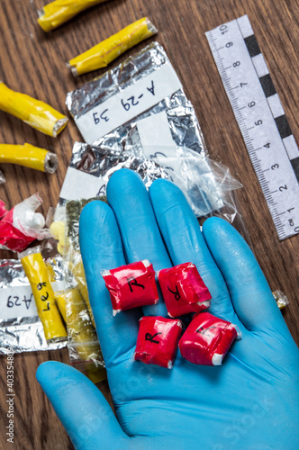 evidence of smuggling traffic: a package with an unknown drug in the hand of an expert against the background of other packages next to the forensic scale