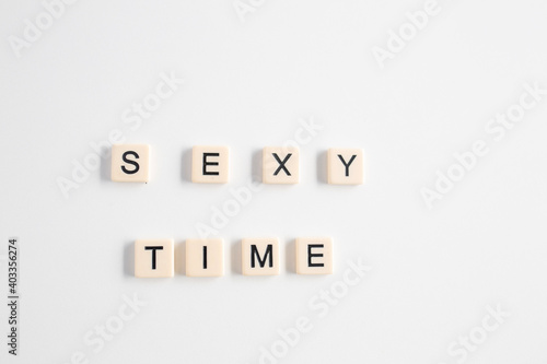 the words sexy times written as a flat lay in wood scrabble tiles on a plain white background
