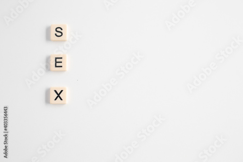 the word sex written as a flat lay in wood scrabble tiles on a plain white background