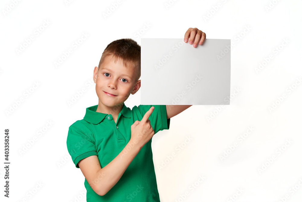 Boy with blank sheet of paper for advertising points his finger Boy with blank sheet of paper for advertising points his finger