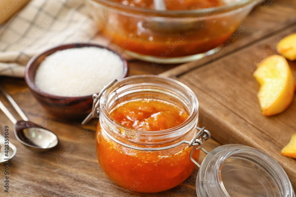 Jar with tasty peach jam on wooden table Jar with tasty peach jam on wooden table