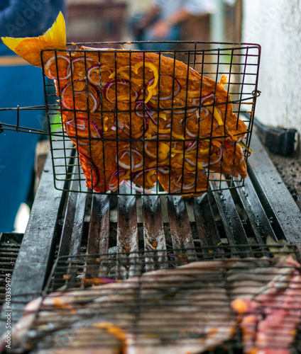 pescado zarandeado y puesto a las brasas en el asador. preparado con cebolla morada, adobo y pimiento amarillo  y montado en la rejilla para asar.