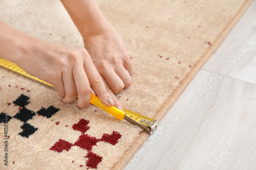 Woman with measuring tape cutting carpet