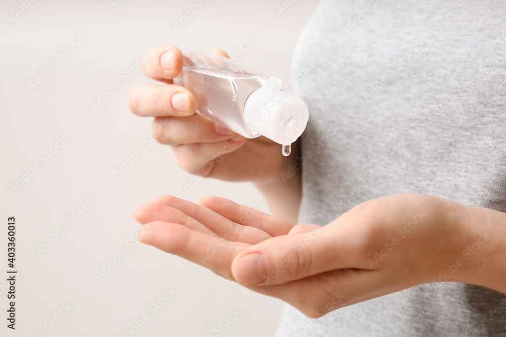 Young woman with sanitizer on light background, closeup Young woman with sanitizer on light background, closeup