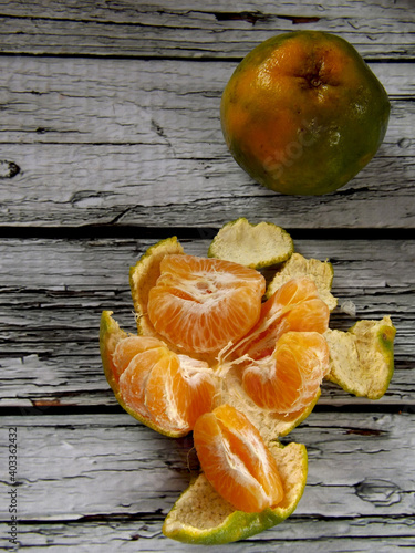 Image of the whole and peeled of jeruk keprok or Indonesian local orange fruits which commonly has green with bit yellow skin. The taste is very refreshing, sweet with bit sour. High angle picture. photo