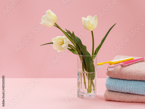 Bouquet of yellow tulips in vase with towels on a pink background.