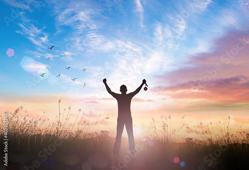 Silhouette of a successful winner raising a medal at sunset, conceptual image of achievement, victory, and ambition.