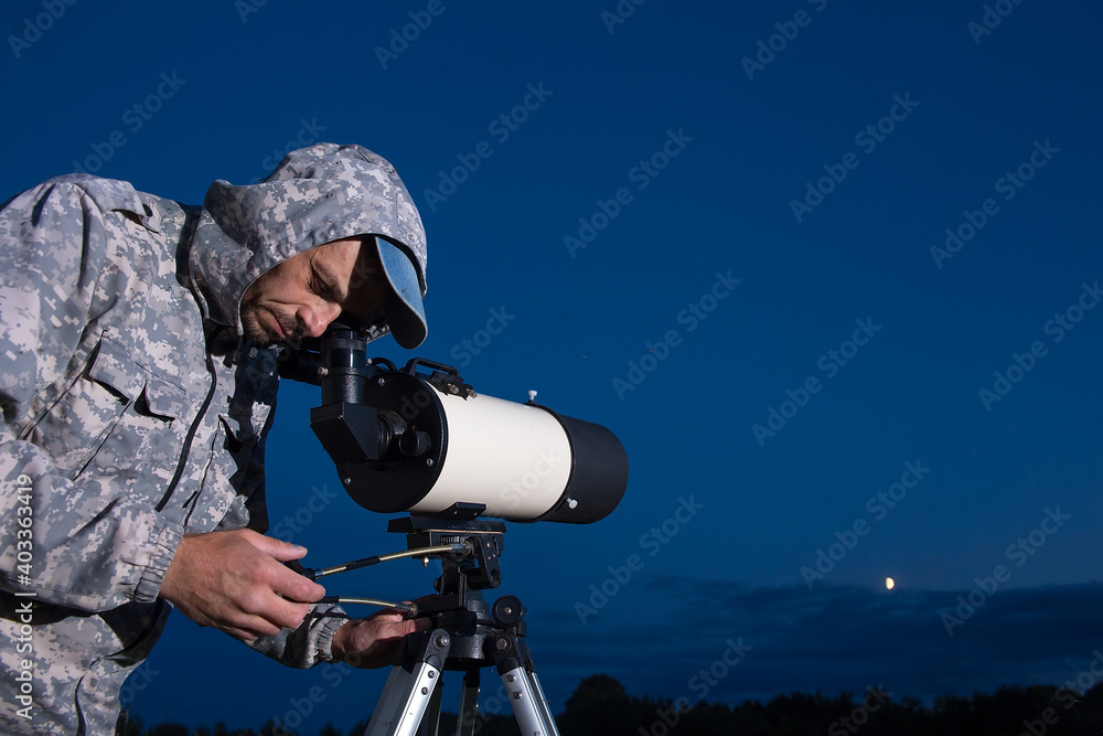 The man looks through a telescope. An amateur astronomer observes the sky.