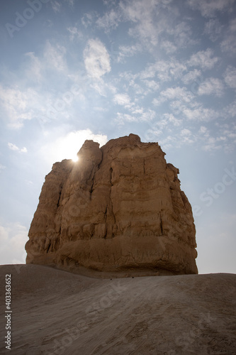 sun peaking behind the rocky mountain alone in the desert