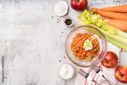 Top view of a bowl of a diet celery salad with carrots and apples, flat lay on concrete background