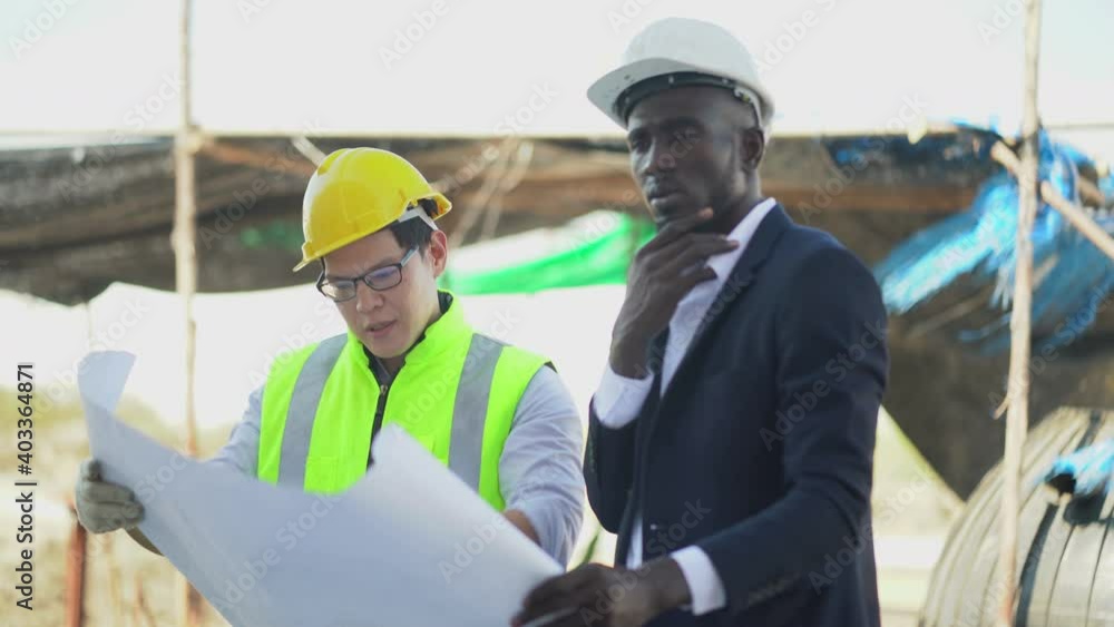 asian foreman and african american architect discuss with blueprint outdoors on construction site at village . contractor worker Inspection with builder . Engineer and foreman . quality control asian foreman and african american architect discuss with blueprint outdoors on construction site at village . contractor worker Inspection with builder . Engineer and foreman . quality control