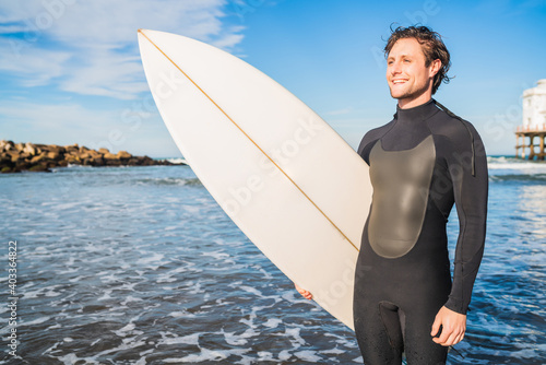 Surfer standing in the ocean with his surfboard.