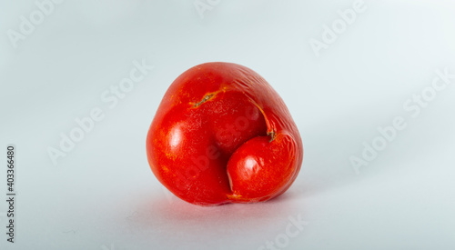 Single odd shaped ugly tomato against white background
