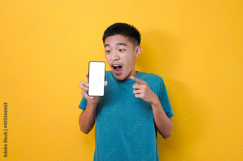 Happy Excited Young Asian man shock pointing blank phone screen for copy space and showing white phone screen at camera Happy Excited Young Asian man shock pointing blank phone screen for copy space and showing white phone screen at camera