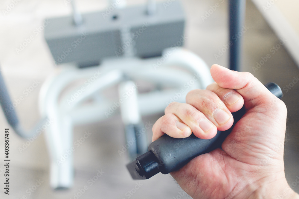 Close up of man's hand pull cable weight in a fitness gym.