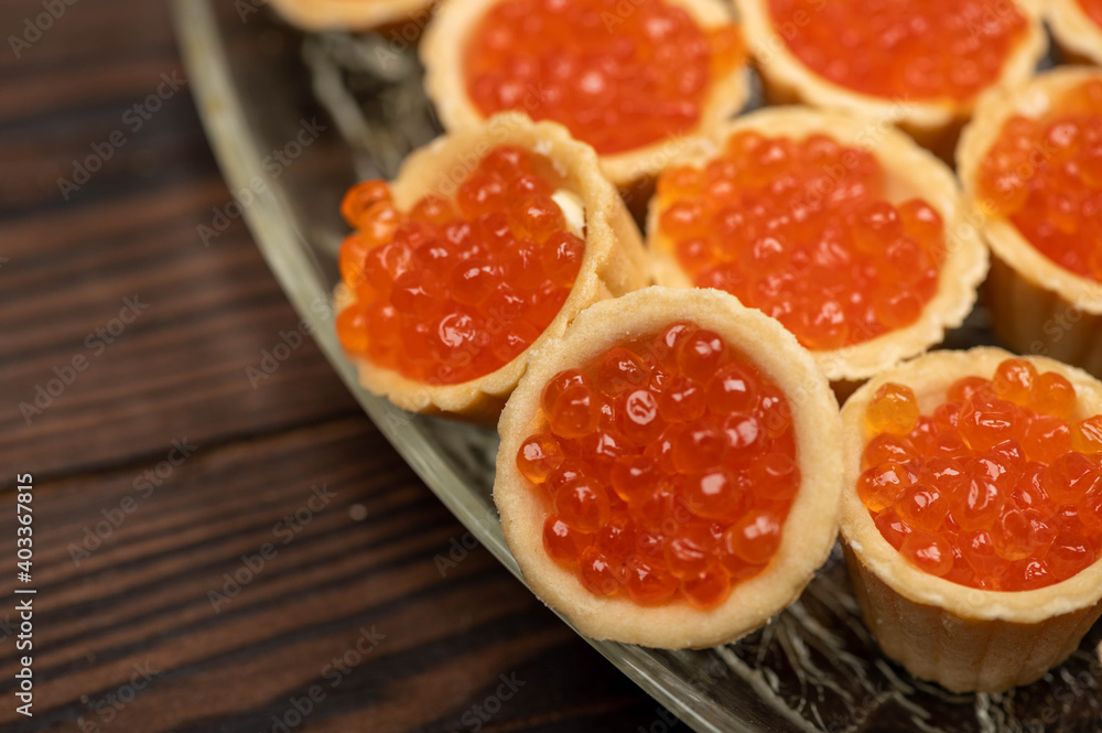 Tartlets with salmon caviar on a platter. Close-up, selective focus. Tartlets with salmon caviar on a platter. Close-up, selective focus.