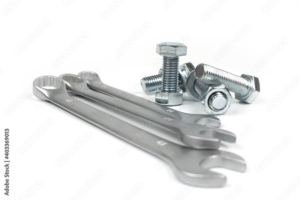 several metal bolts and nuts with wrenches on a white background several metal bolts and nuts with wrenches on a white background