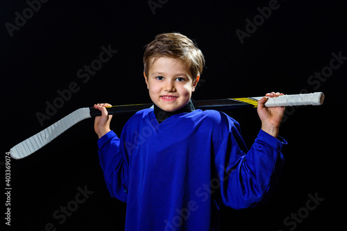 boy hockey player with a stick in a blue uniform on a black background