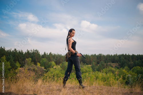 Girl with a pistol in nature. Against the background of yellow grass. The female army on the hunt. © Вероника Преображенс