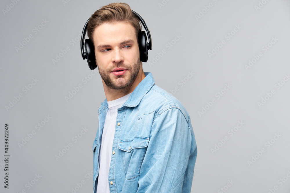 Close up portrait of cheerful young man enjoying listening to music wearing casual jeans outfit Close up portrait of cheerful young man enjoying listening to music wearing casual jeans outfit