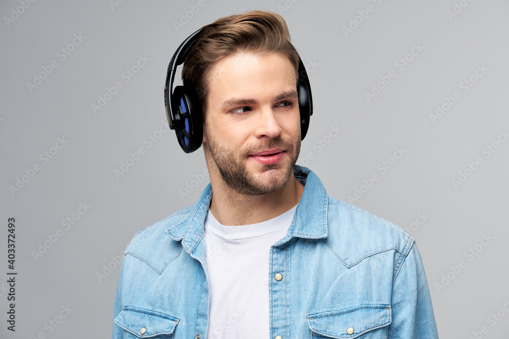 Close up portrait of cheerful young man enjoying listening to music wearing casual jeans outfit - obrazy, fototapety, plakaty 
