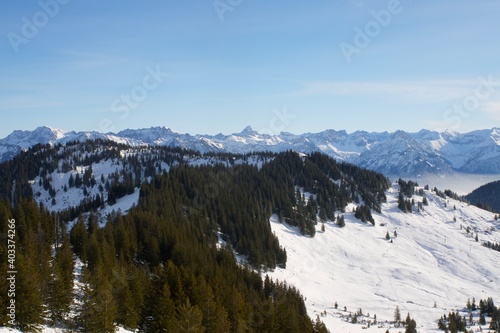Winterliche Landschaft der schneebedeckten bayerischen Alpen vor blauem Himmel im Sonnelicht