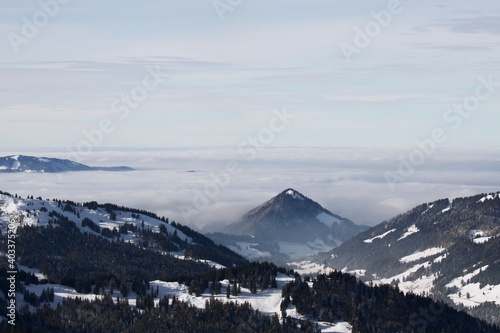 Winterlandschaft der schneebedeckten bayerischen Alpen über Wolken vor blauem Himmel