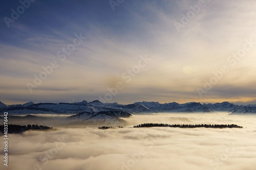 Winterlandschaft der schneebedeckten bayerischen Alpen über Wolken vor blauem Himmel