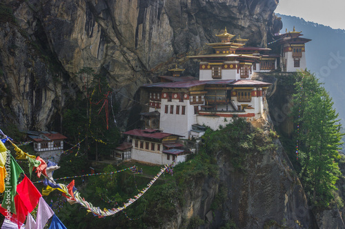 Scenic landscape view of cliff hanging Taktsang buddhist monastery aka Tiger's Nest with traditional prayer flags in foreground, Paro, Bhutan photo
