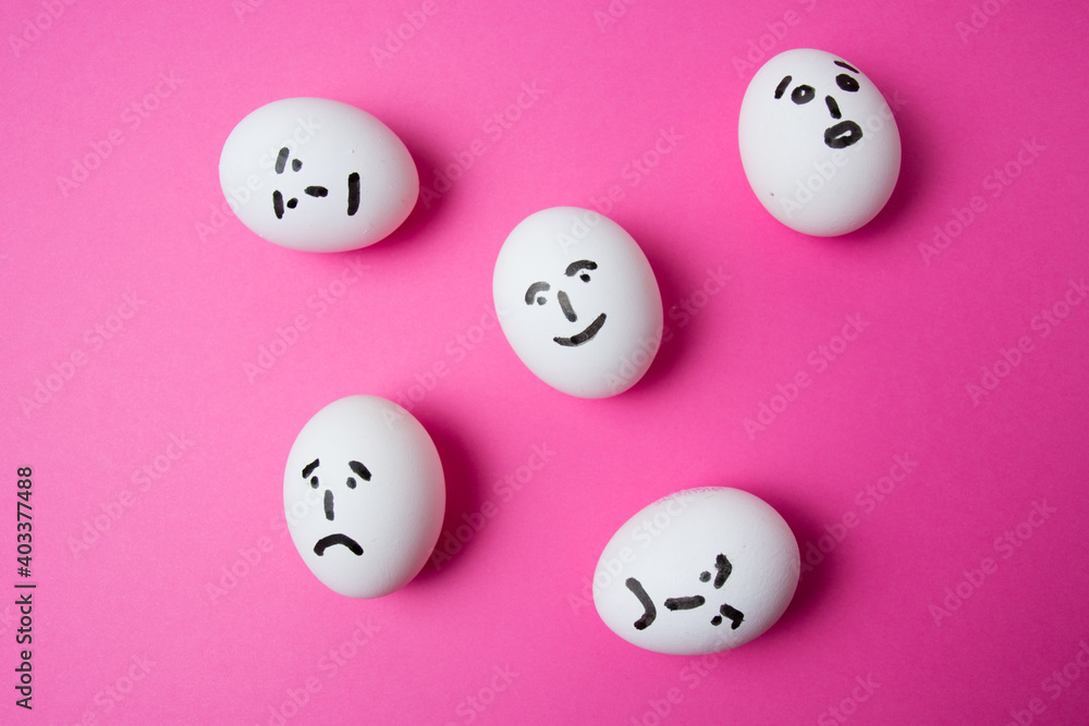 Eggs with different faces on a pink background with copy space. The concept of relations in society. Eggs with different faces on a pink background with copy space. The concept of relations in society.