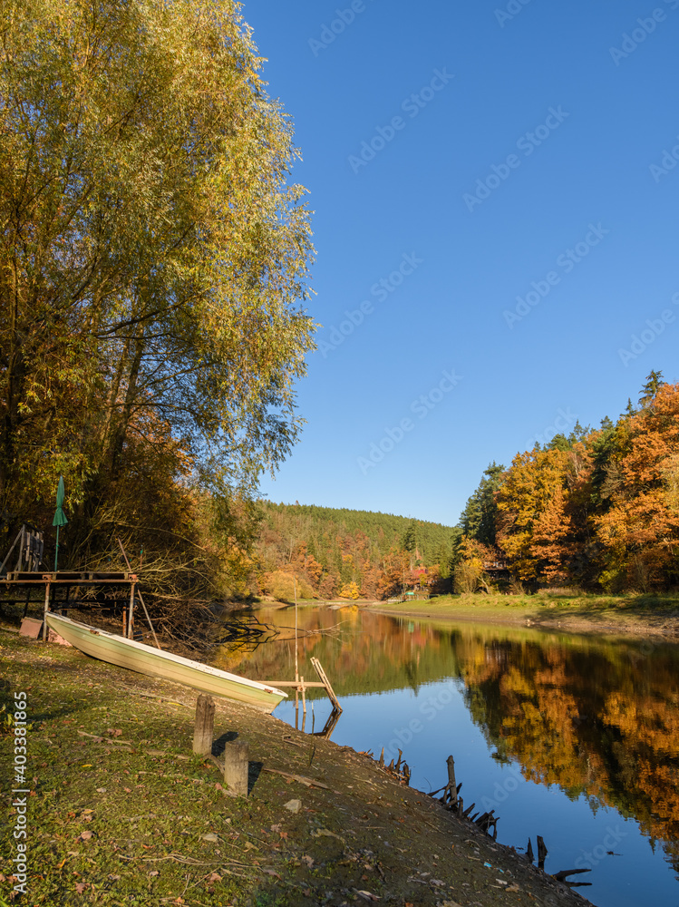 autumn view at river Mze next city Stribro with boat and reflections in water on sunny day autumn view at river Mze next city Stribro with boat and reflections in water on sunny day