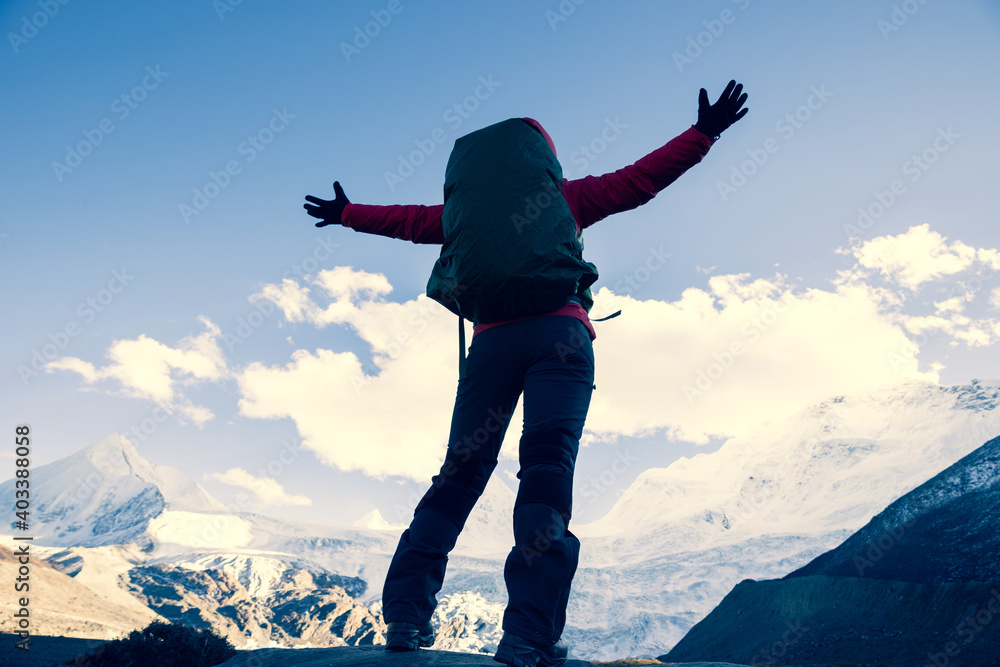 Successful woman backpacker hiking in winter mountains