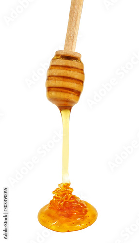 Honey dripping from wooden honey dipper, isolated on white background
